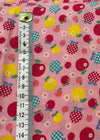 Fabric with apple pattern on a pink background, measured with a ruler.