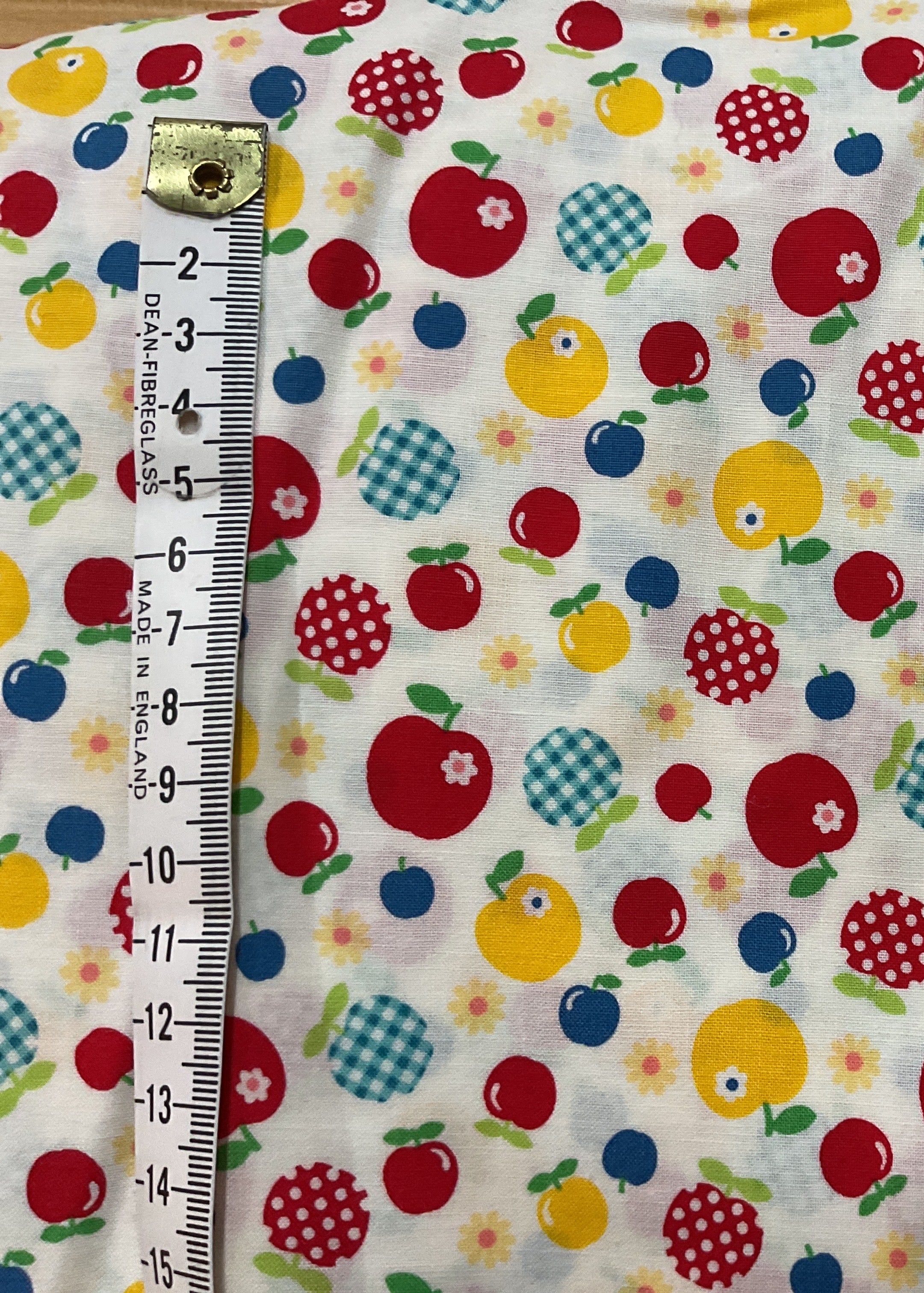 Fabric with colorful apple pattern and ruler for scale