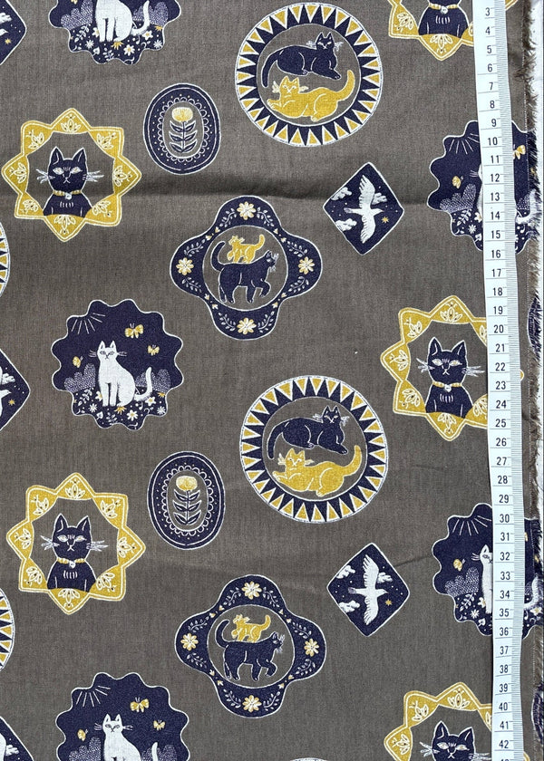 Patterned fabric with cat designs on a gray background, measured by a ruler.