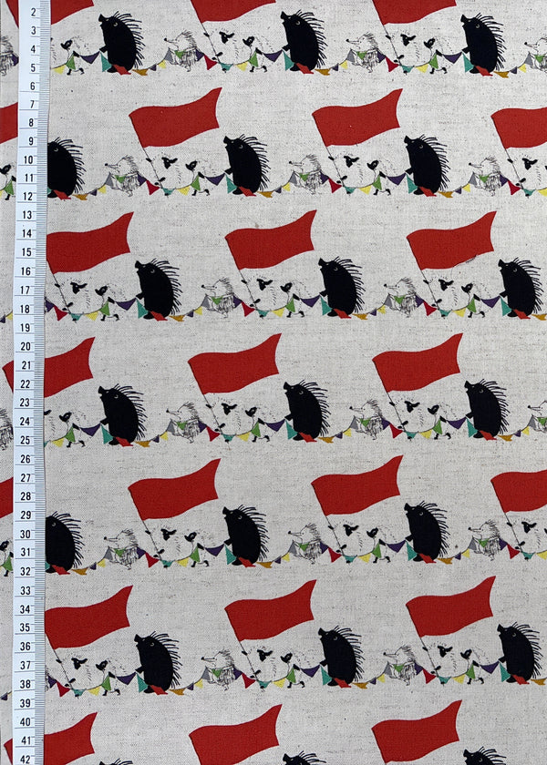 Fabric with a pattern of red flags and black and white shapes on a white background, with a ruler for scale.