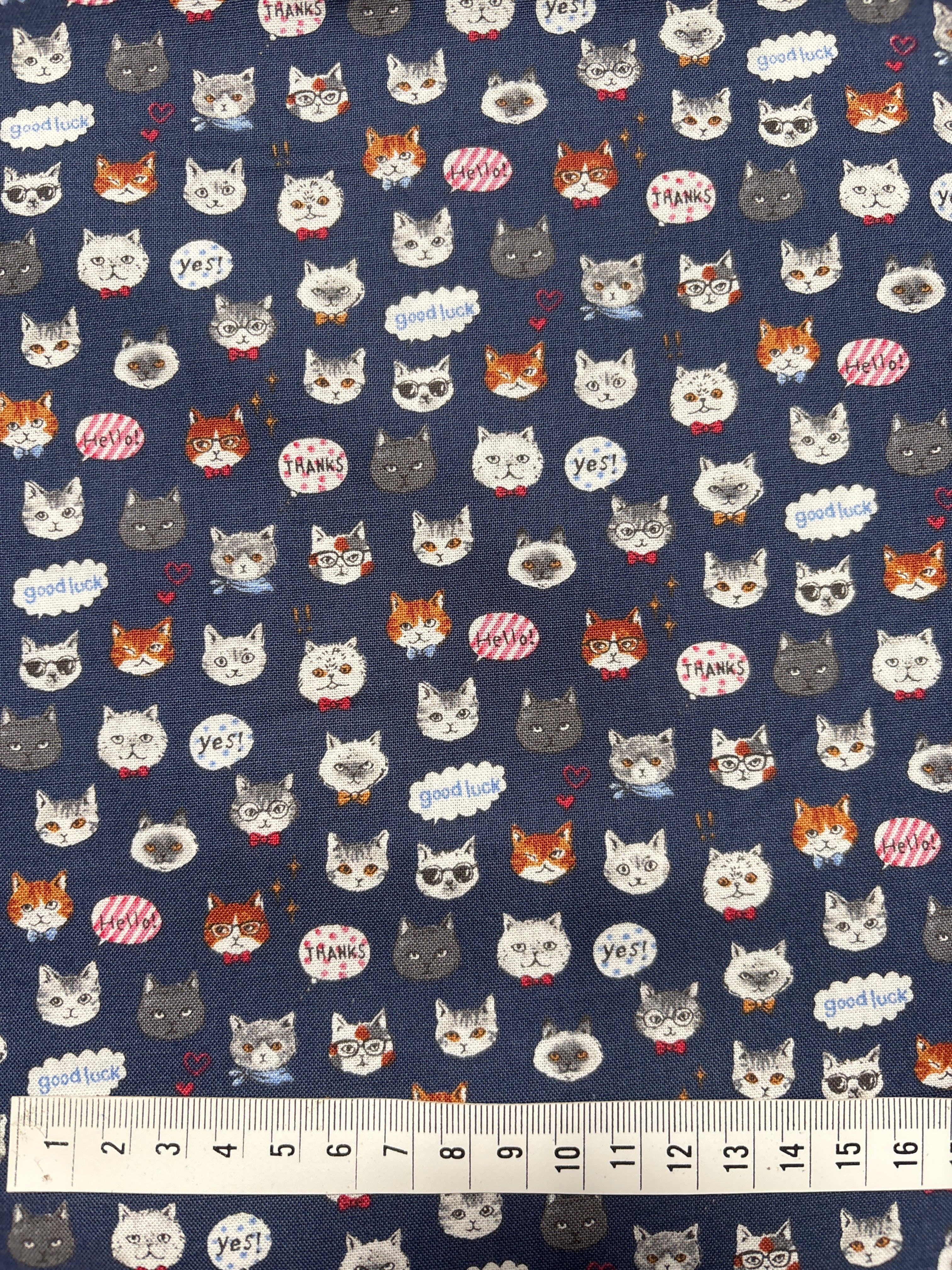 Patterned fabric with cartoonish animal faces on a blue background, accompanied by a ruler for scale.