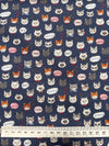 Patterned fabric with cartoonish animal faces on a blue background, accompanied by a ruler for scale.