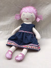Doll with a blue dress and pink shoes on a light gray background