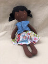 Handmade doll with a blue top and colorful skirt on a beige background