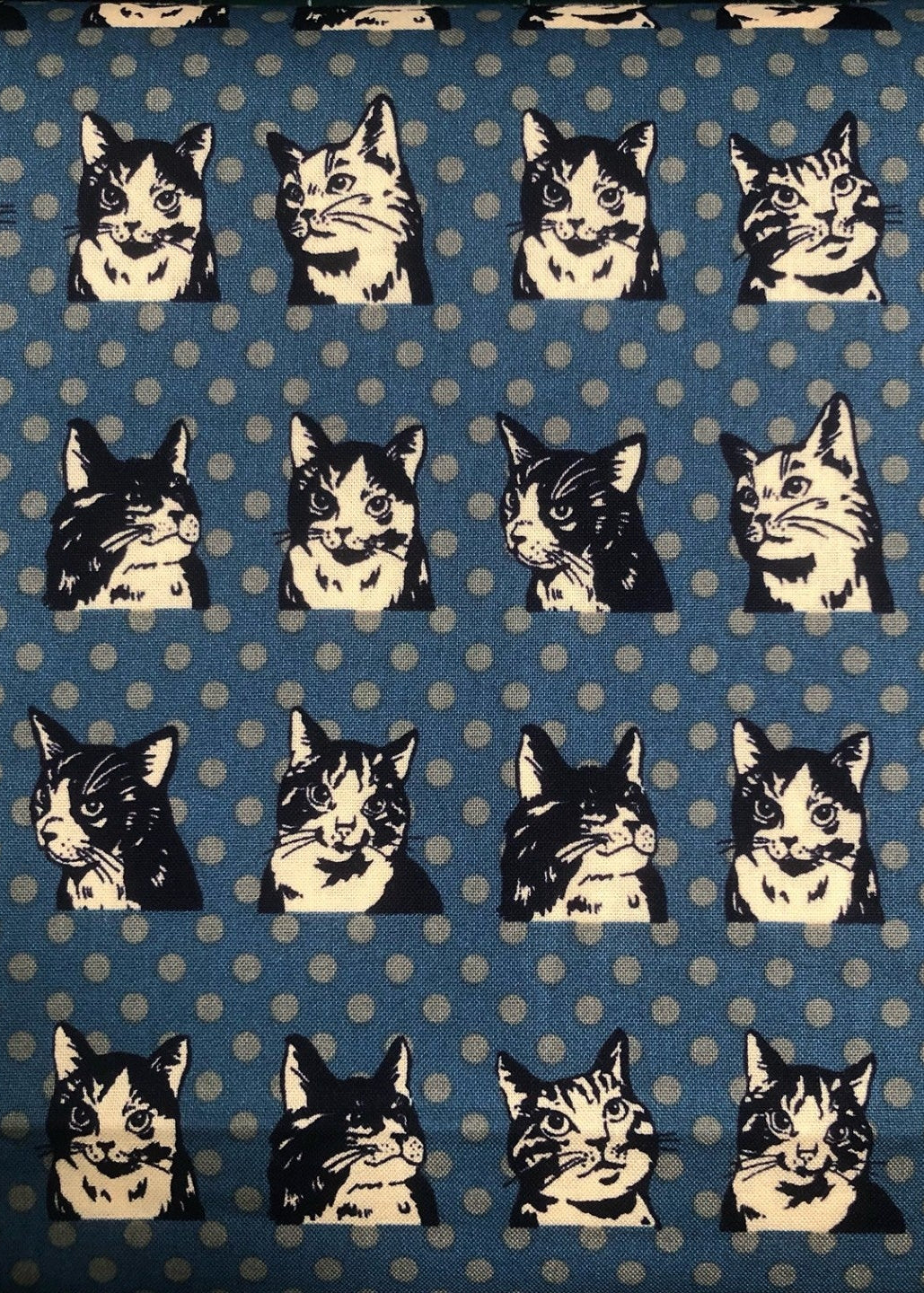 Pattern of black and white cat faces on a blue background with white polka dots