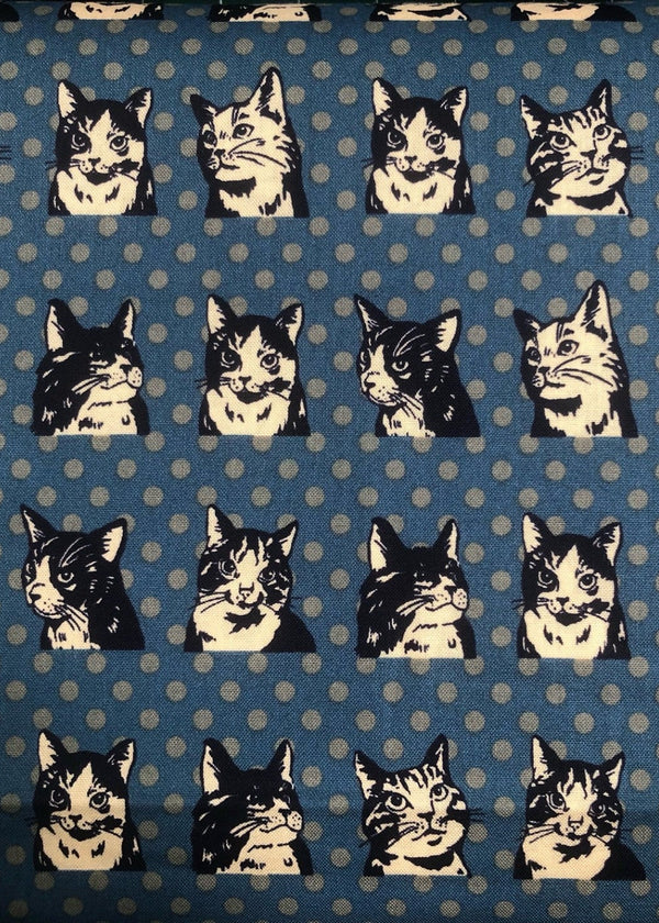 Pattern of black and white cat faces on a blue background with white polka dots